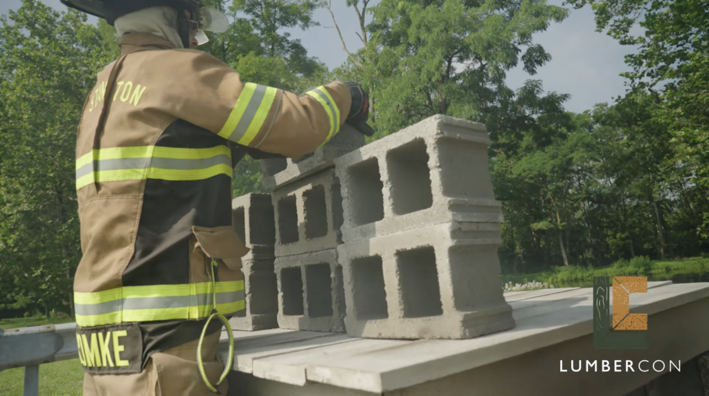 A firefighter stacking concrete blocks onto the LumberCon deck surface to load it before the burn.