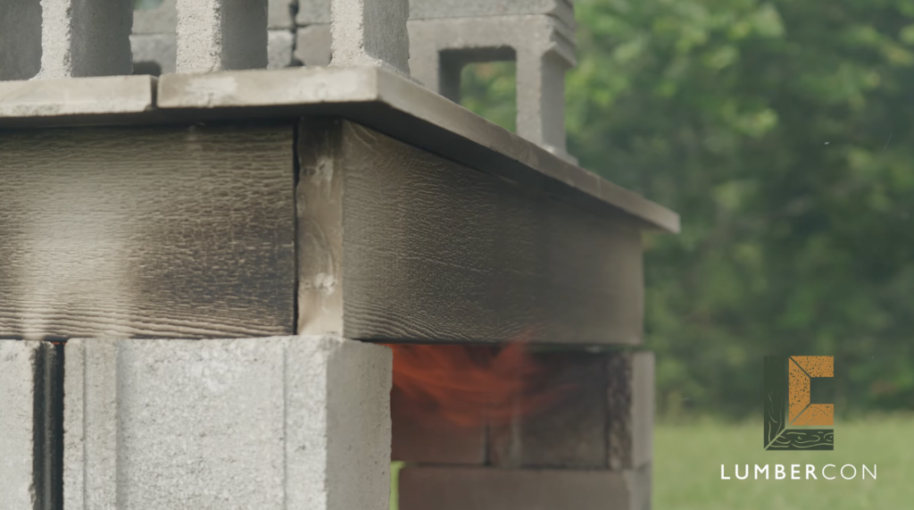 Close-up of a charred LumberCon plank edge with flame beneath it, the concrete surface still intact.
